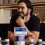 A man enjoying wellbeing surrounded by supplement bottles in a modern kitchen.